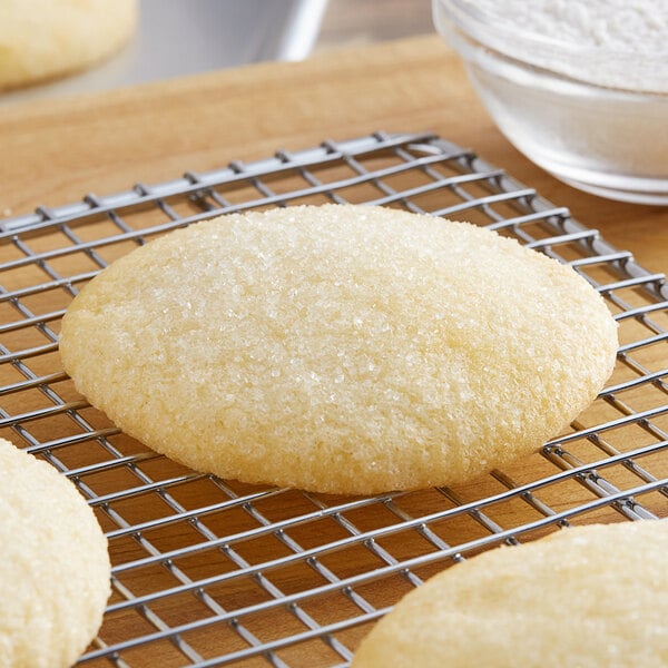 A sugar cookie on a cooling rack next to a bowl of ADM Premium Baker's Flour.
