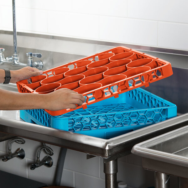 A person holding a blue and orange Carlisle glass rack extender.