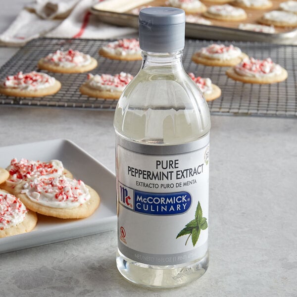 A bottle of McCormick Culinary Pure Peppermint Extract next to cookies on a counter.