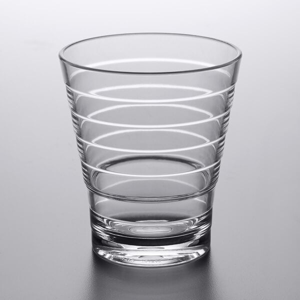 A close up of a clear GET Cirq double rocks glass with a curved design and a white stripe.