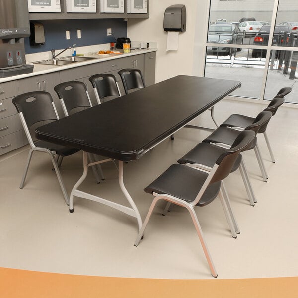 A black plastic Lifetime folding table and chairs in a room.
