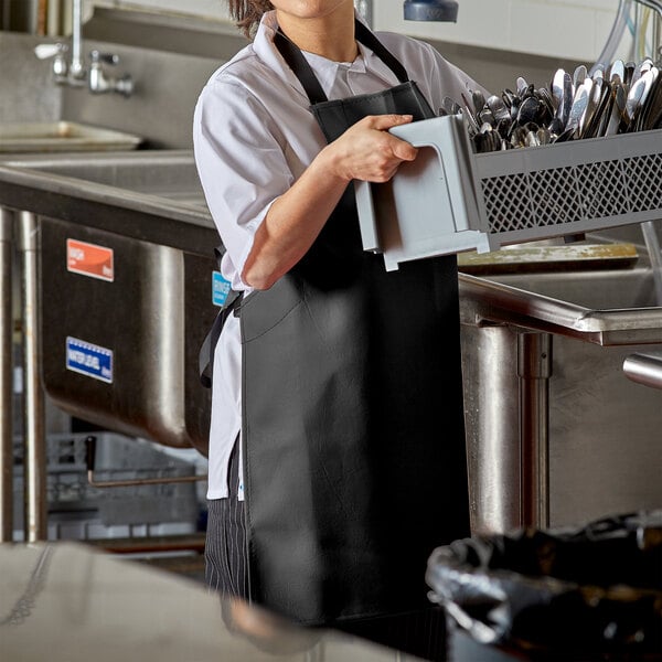 A woman wearing a black Intedge vinyl dishwasher apron.