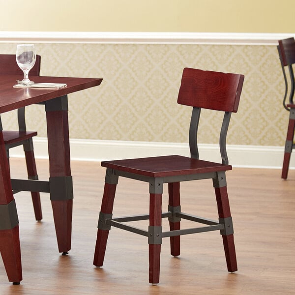 A Lancaster Table & Seating Rustic Industrial dining chair with mahogany finish on a table in a restaurant dining area.