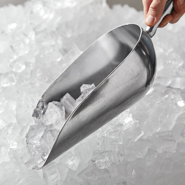 A person using a Vollrath cast aluminum ice scoop to scoop ice.