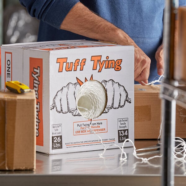 A person holding a brown rectangular box of 1-Ply Polypropylene Industrial Twine with a hole in it.
