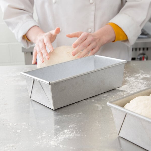A person kneading dough in a Chicago Metallic aluminized steel bread loaf pan.