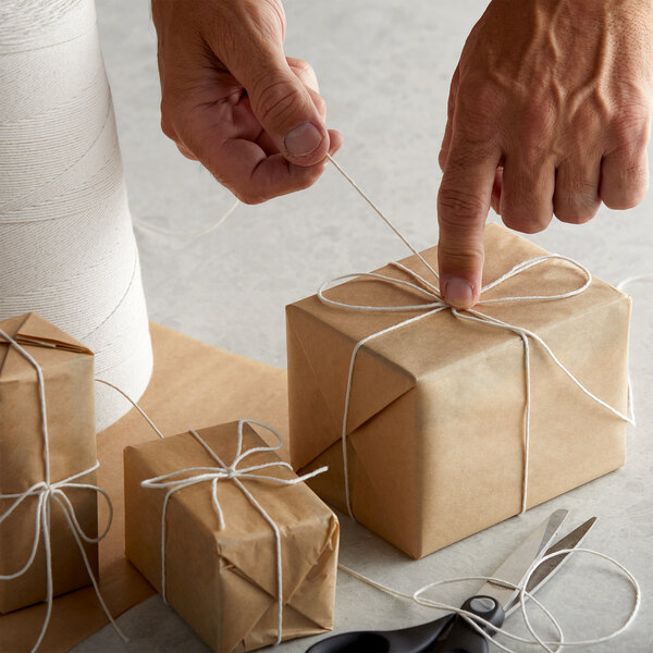 Hands holding white 8-ply polyester/cotton twine tied to a brown package.