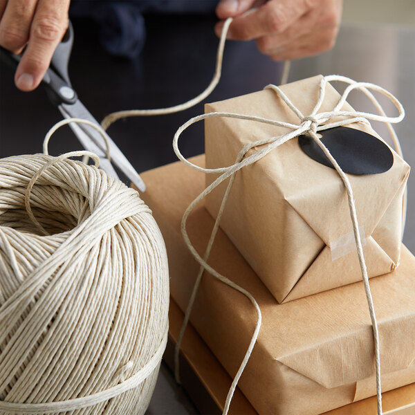 A person cutting a string of 4-Ply Long-Fiber Hemp Spring Twine with scissors.