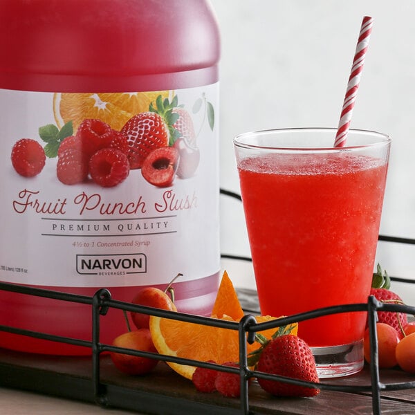 A bottle of Narvon Fruit Punch Slushy concentrate next to a glass of fruit punch.