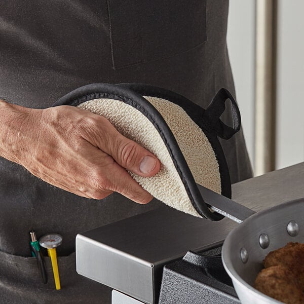 A person using a SafeMitt pot holder to hold a hot pan