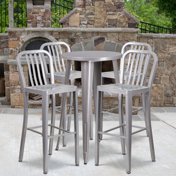 A Flash Furniture silver metal bar height table with four chairs with vertical slat backs on an outdoor patio.