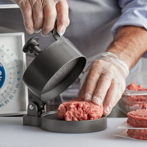 A person using a Weston hamburger press to make a meat patty.