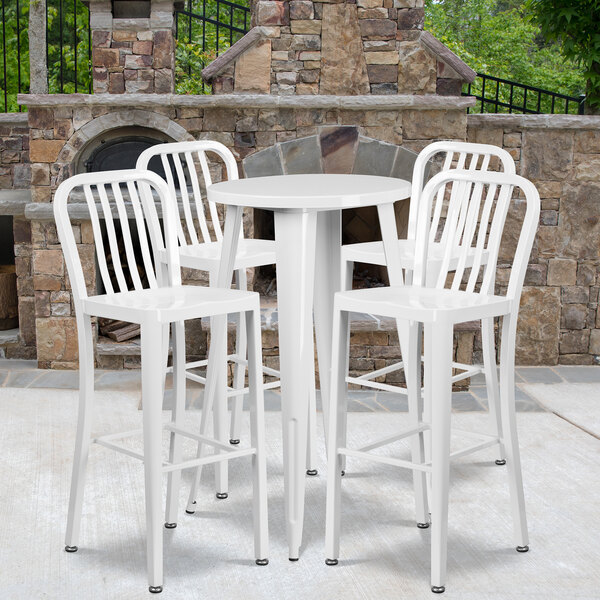A Flash Furniture white metal round bar height table with four white chairs.