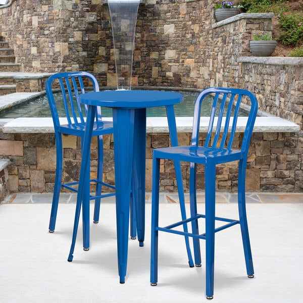 A blue metal table and two blue stools on an outdoor patio.