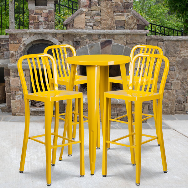 A Flash Furniture yellow metal bar height table with yellow chairs on an outdoor patio.