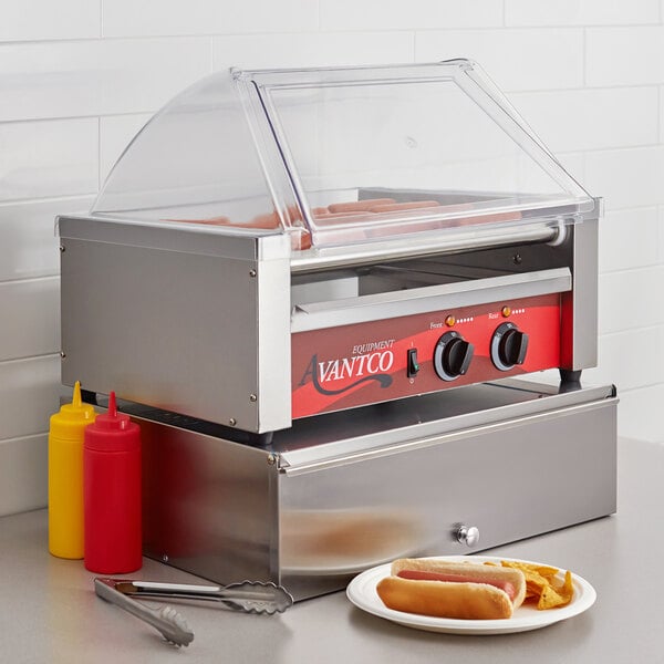 An Avantco hot dog roller grill with hot dogs and buns on a counter.