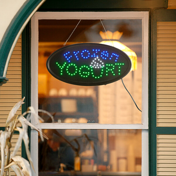 A white LED oval sign that says "frozen yogurt" with lights on it.