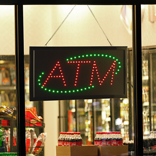 A lit up red and green rectangular LED ATM sign.