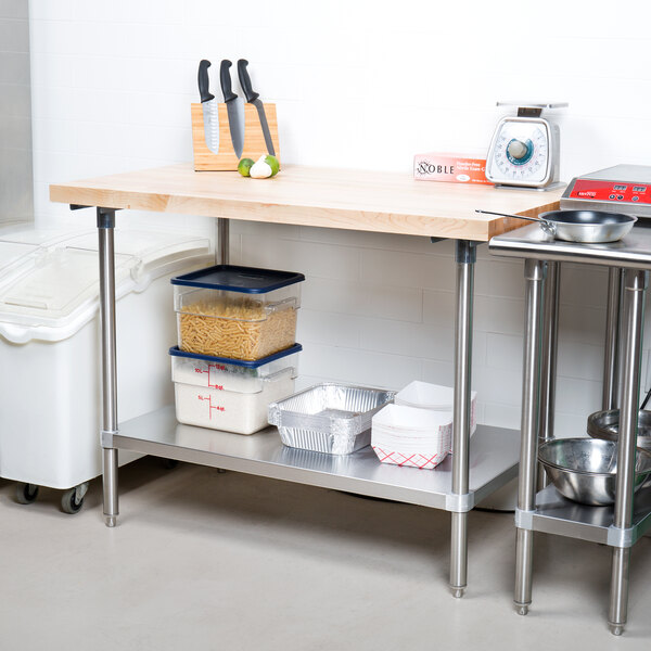 A wood top work table with a stainless steel base and metal undershelf in a professional kitchen.