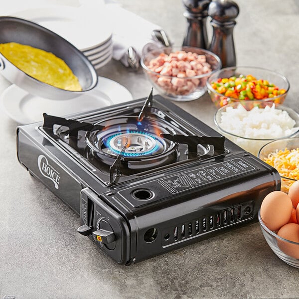 A Choice portable stove with a blue flame heating food in a pan on a table.