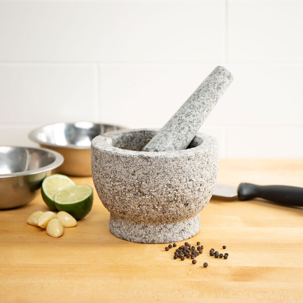 A Fox Run granite mortar and pestle on a table with lime and pepper.