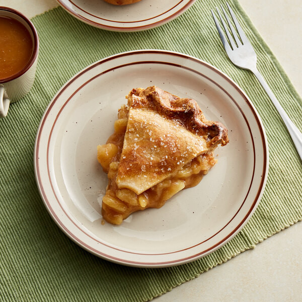 A slice of apple pie on an Acopa brown speckle narrow rim stoneware plate with a fork and cup of liquid.