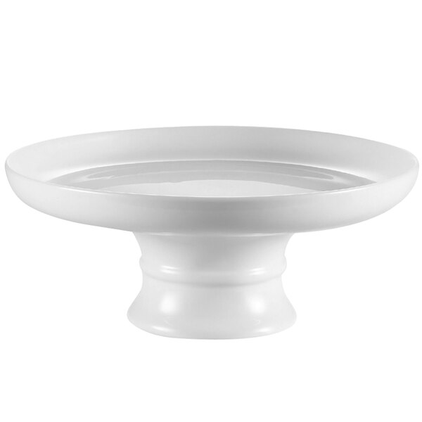 A white China coupe cake stand with a round rim on a white plate.