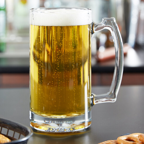 An Anchor Hocking beer mug filled with beer on a table.