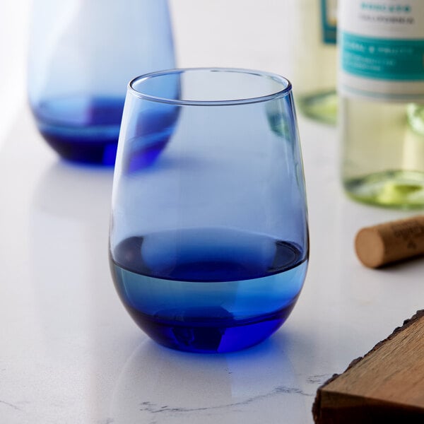 A Libbey Tidal Blue stemless white wine glass filled with blue liquid on a table.