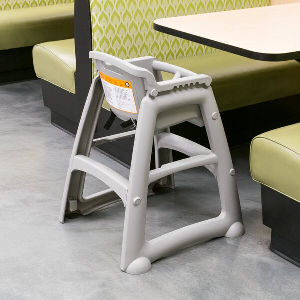 A Rubbermaid restaurant high chair with a yellow seat on a white table.