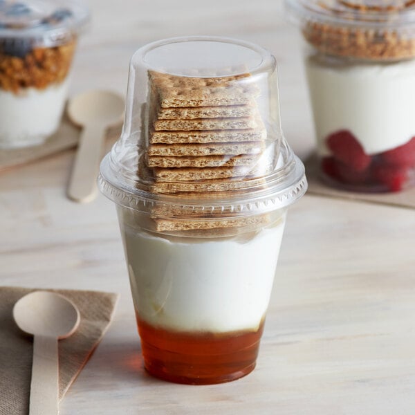 A 12 oz. parfait cup filled with yogurt and a stack of crackers on top.