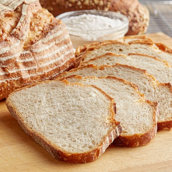 A bowl of ADM High Gluten Flour next to a sliced loaf of bread.