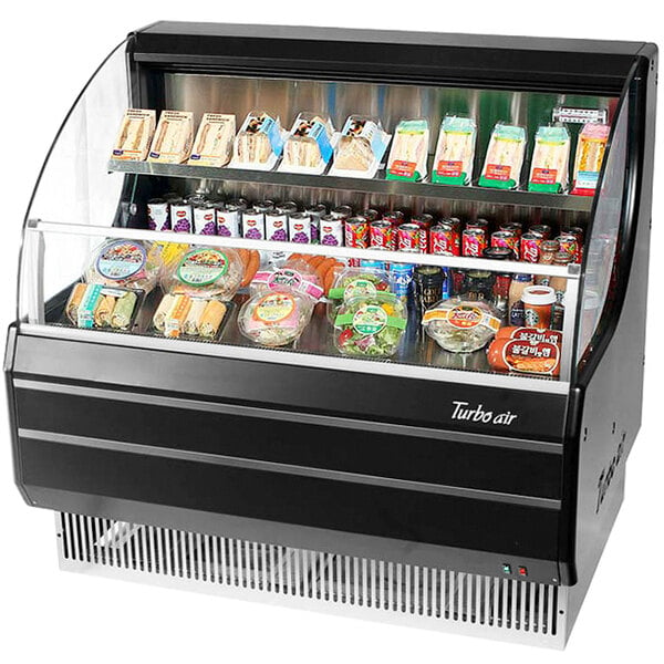 A black Turbo Air low profile horizontal air curtain display case with food in plastic containers.