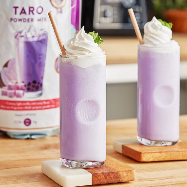 A close-up of a purple drink with whipped cream and mint leaves with a straw in it.