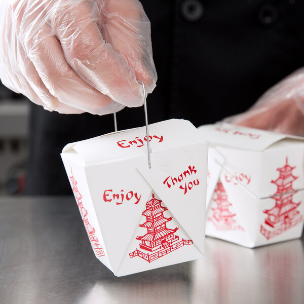 A person in gloves holding a white Fold-Pak take-out box with red writing.