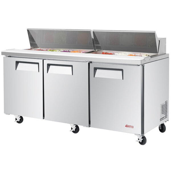 A Turbo Air stainless steel refrigerated sandwich prep table with 3 doors and trays.