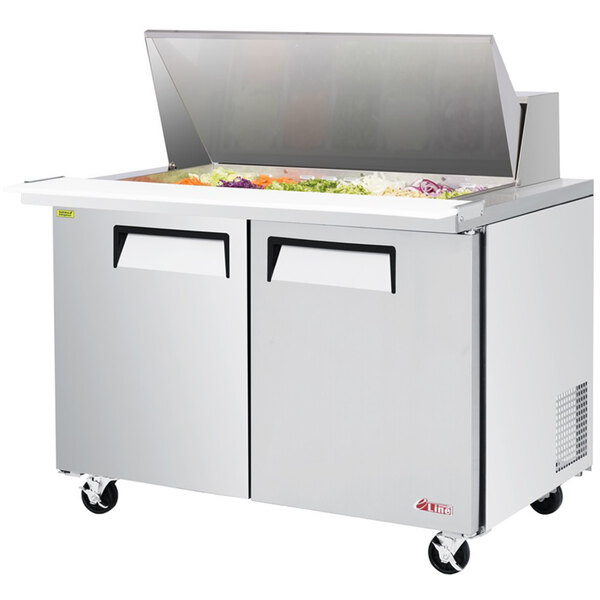A Turbo Air stainless steel refrigerated salad prep table with a lid open and food inside.