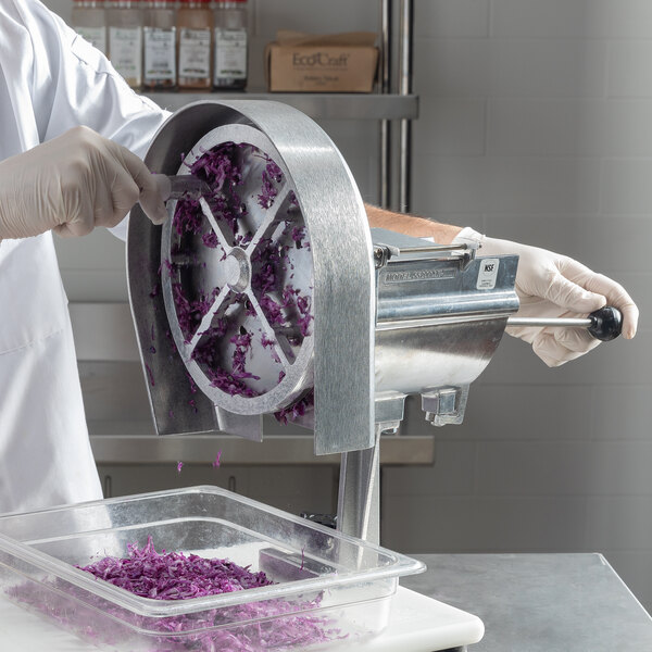 A person in white gloves using a Nemco Easy Slicer to cut purple cabbage.
