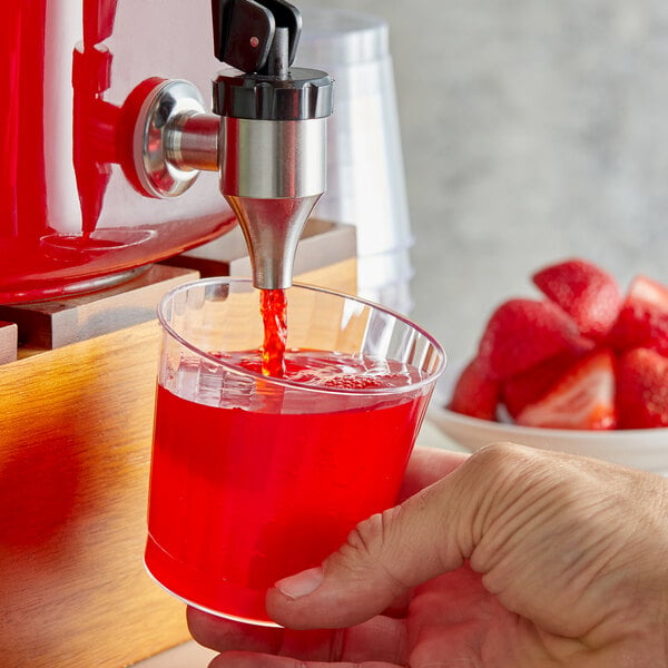 A hand pouring Narvon Strawberry Beverage into a glass.