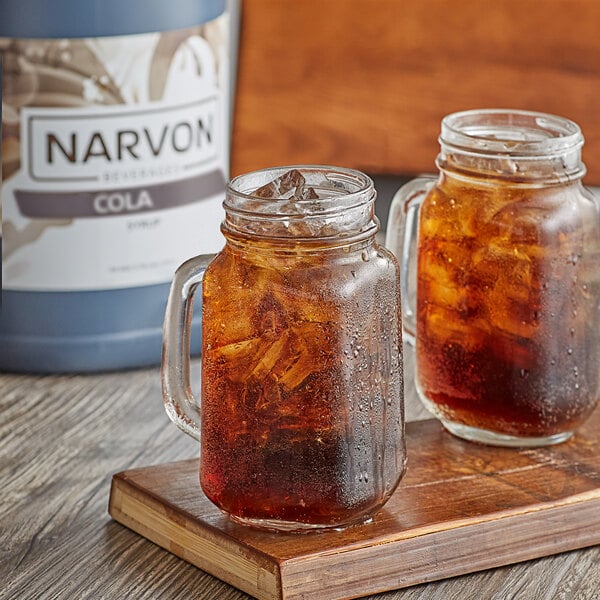 A couple of glass jars with ice and Narvon Old Fashioned Cola on a wooden surface.