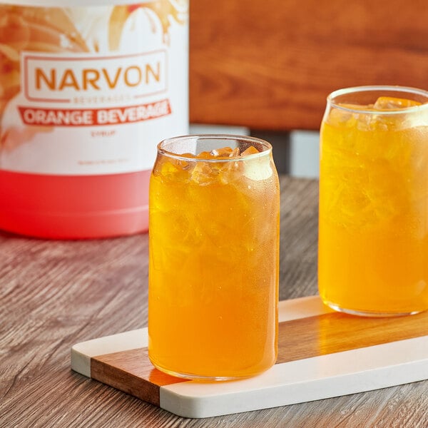 A couple of glasses of Narvon orange beverage on a table.