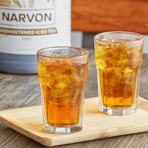 A pair of glasses of Narvon iced tea with ice on a wooden tray.