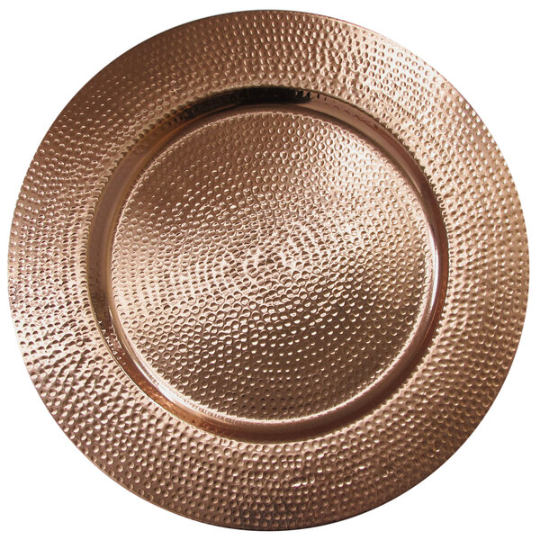 A close-up of a Charge It by Jay copper hammered charger plate with a circular design.