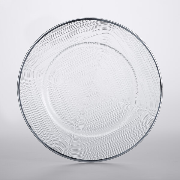 A clear glass Charge It by Jay charger plate with a silver weave pattern on the rim.