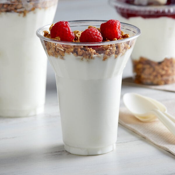 A 12 oz. PET parfait cup filled with yogurt, granola, and raspberries with a spoon.