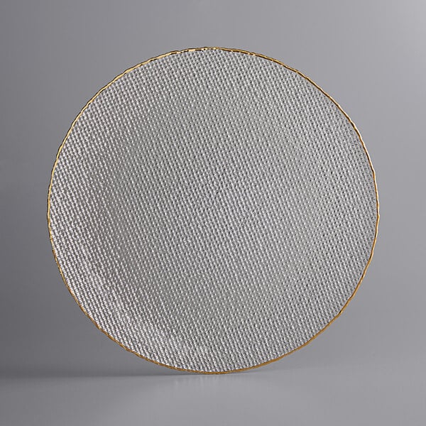 A white round glass charger plate with a textured clear center and a gold rim.