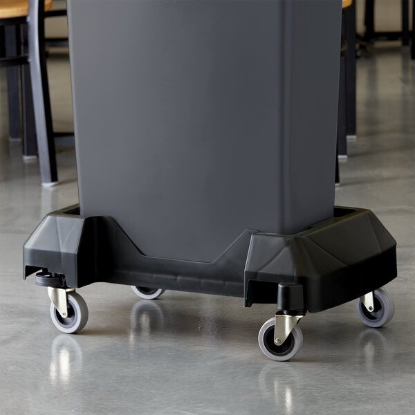 A black rectangular Lavex Slim Trash Can Dolly with a black trash can on top.