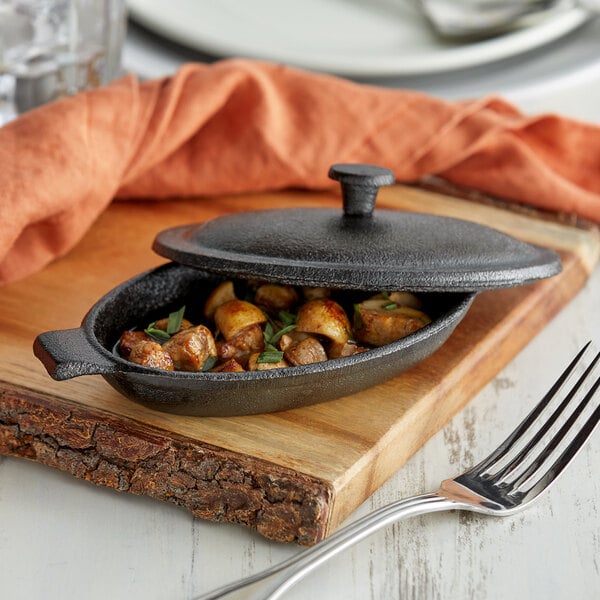 A Vollrath mini cast iron casserole dish with food in it on a table with a fork.