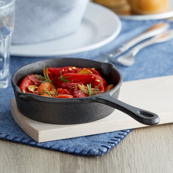 A Vollrath mini cast iron skillet of food with tomatoes and peppers.