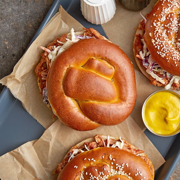 A tray of sandwiches made with J & J Snack Foods Bavarian Bakery soft pretzel rolls with mustard and ketchup on the side.